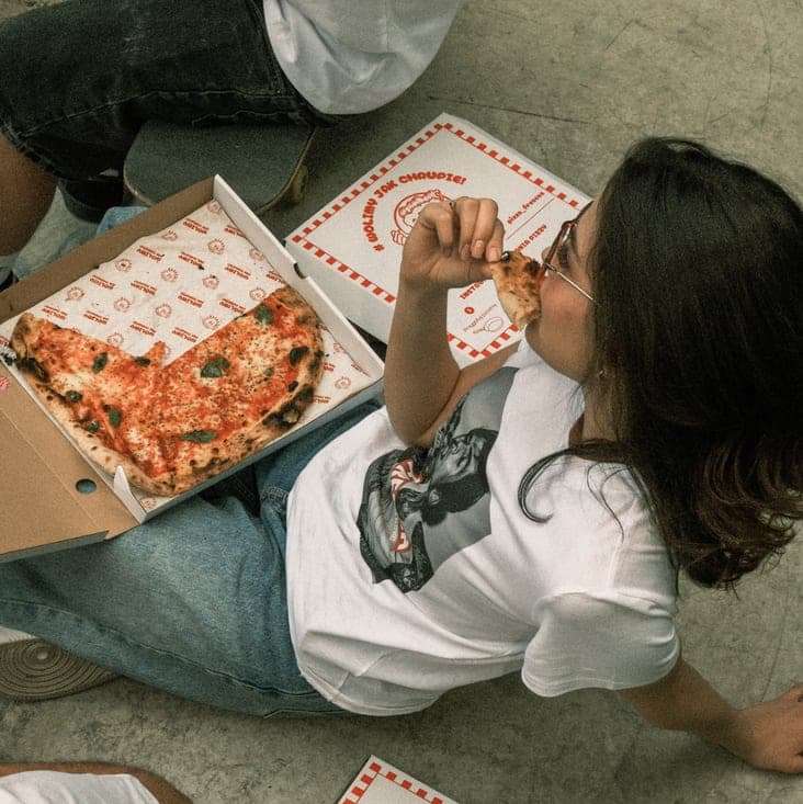 Dziewczynka jedząca pizzę z pudełka